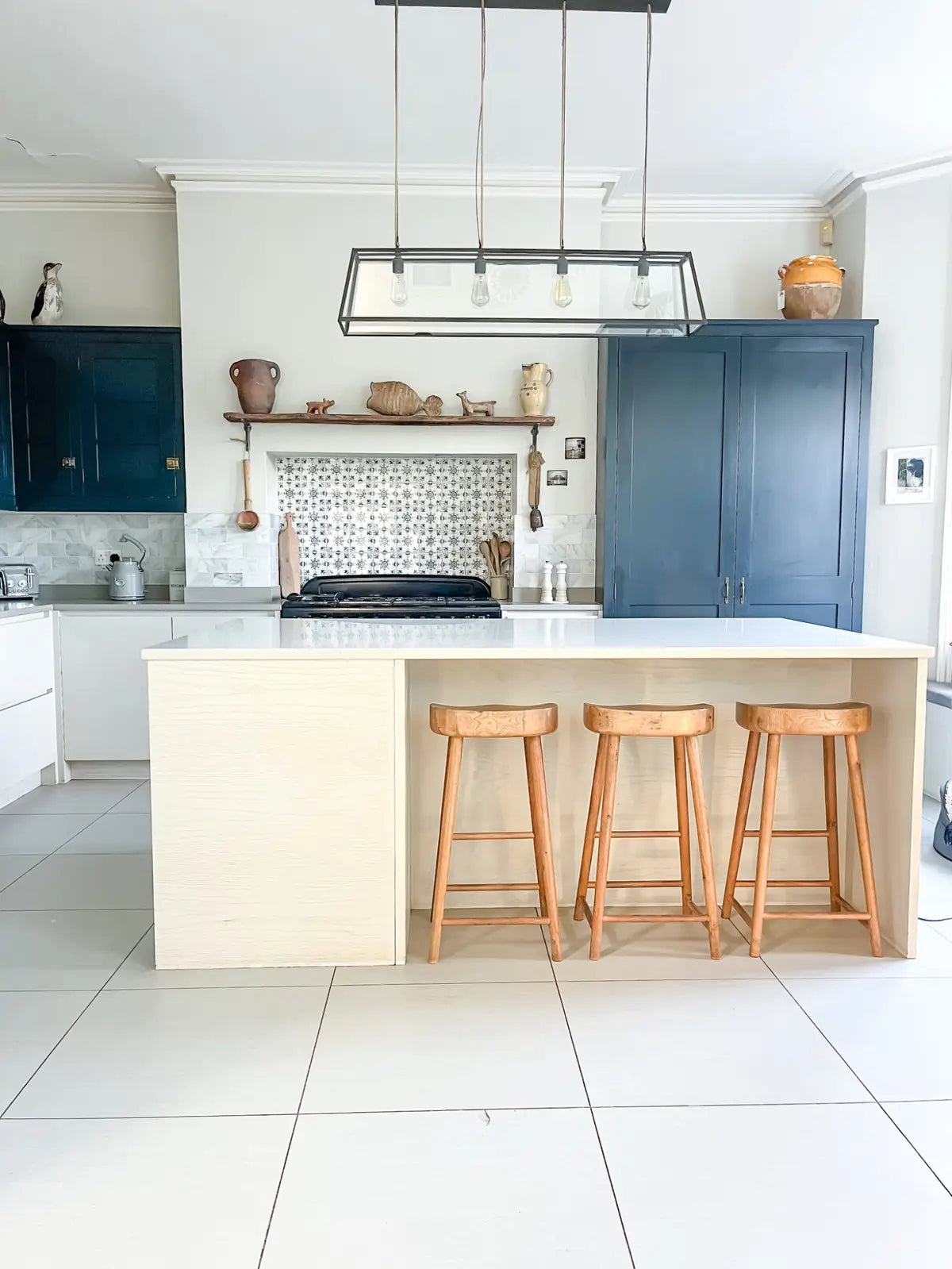 Period kitchen with patterned tiled splashback and rustic wooden shelf styling