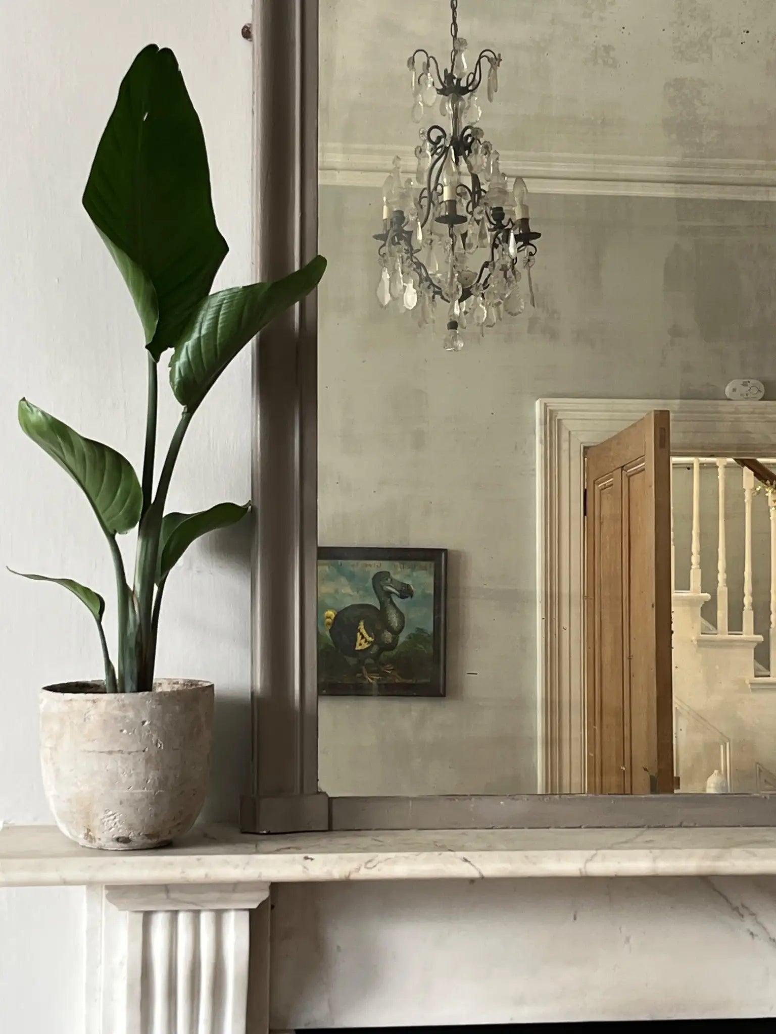 Elegant view of the marble fireplace, American Folk Bird art on the wall and the stairs in the hallway.
